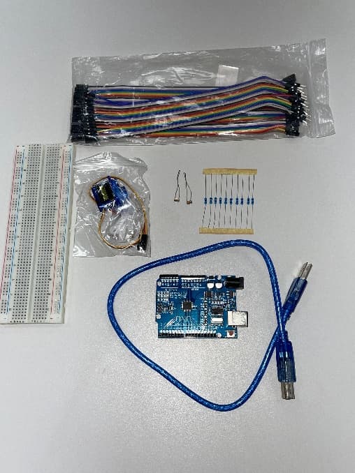 Breadboard, jumper wires, SG90 servo, LDRs, resistors, Arduino UNO, and USB cable arranged before assembly
