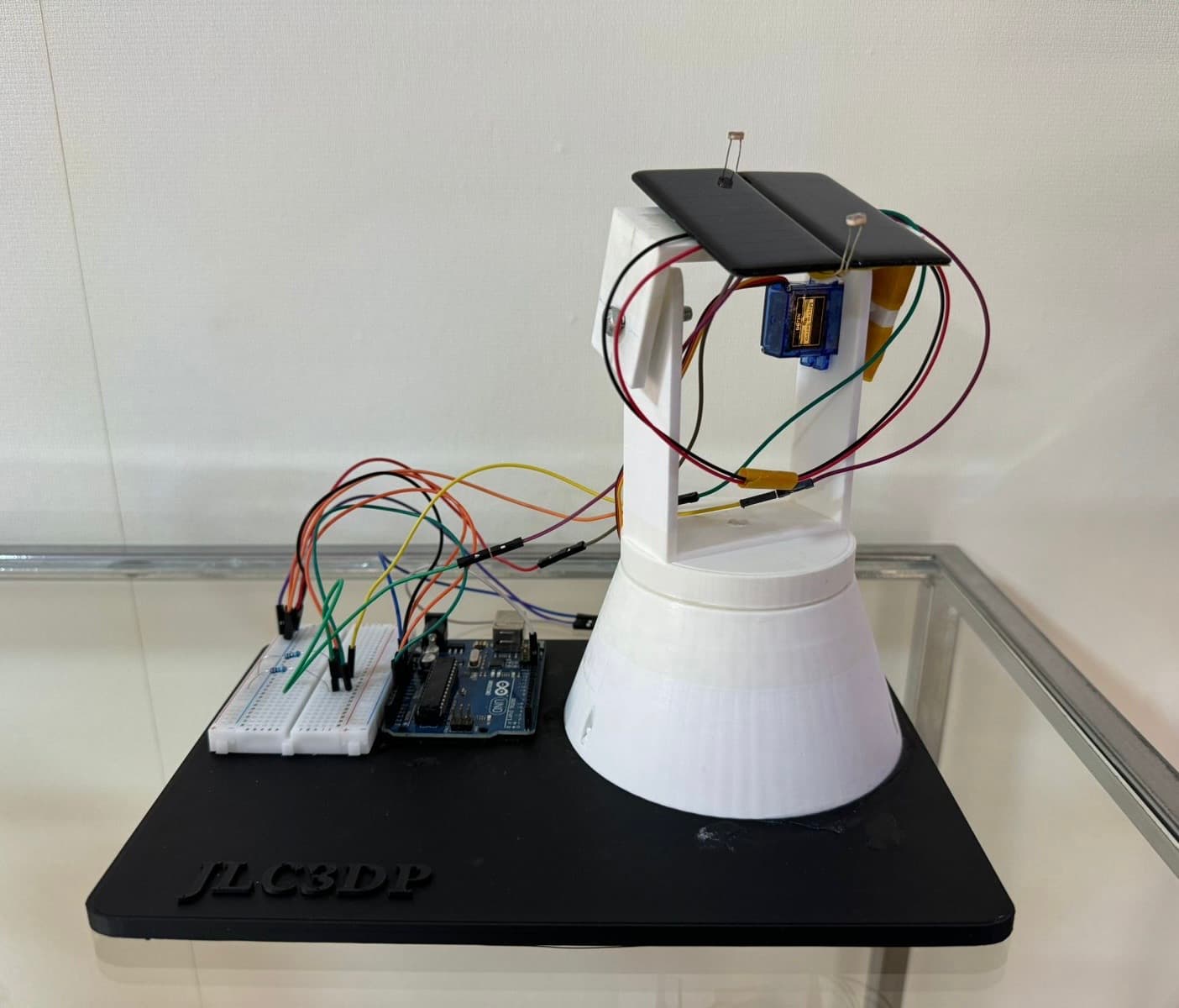 Completed Arduino solar tracker prototype with two light sensors and a servo-driven panel frame.